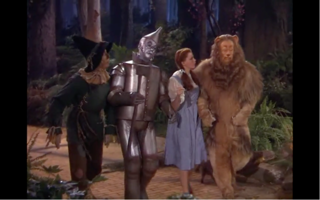 Photogramme du Magicien d’Oz avec de gauche à droite, Ray Bolger (l’Épouvantail), Jack Haley (le Bûcheron), Judy Garland (Dorothée) et Bert Lahr (le Lion) 